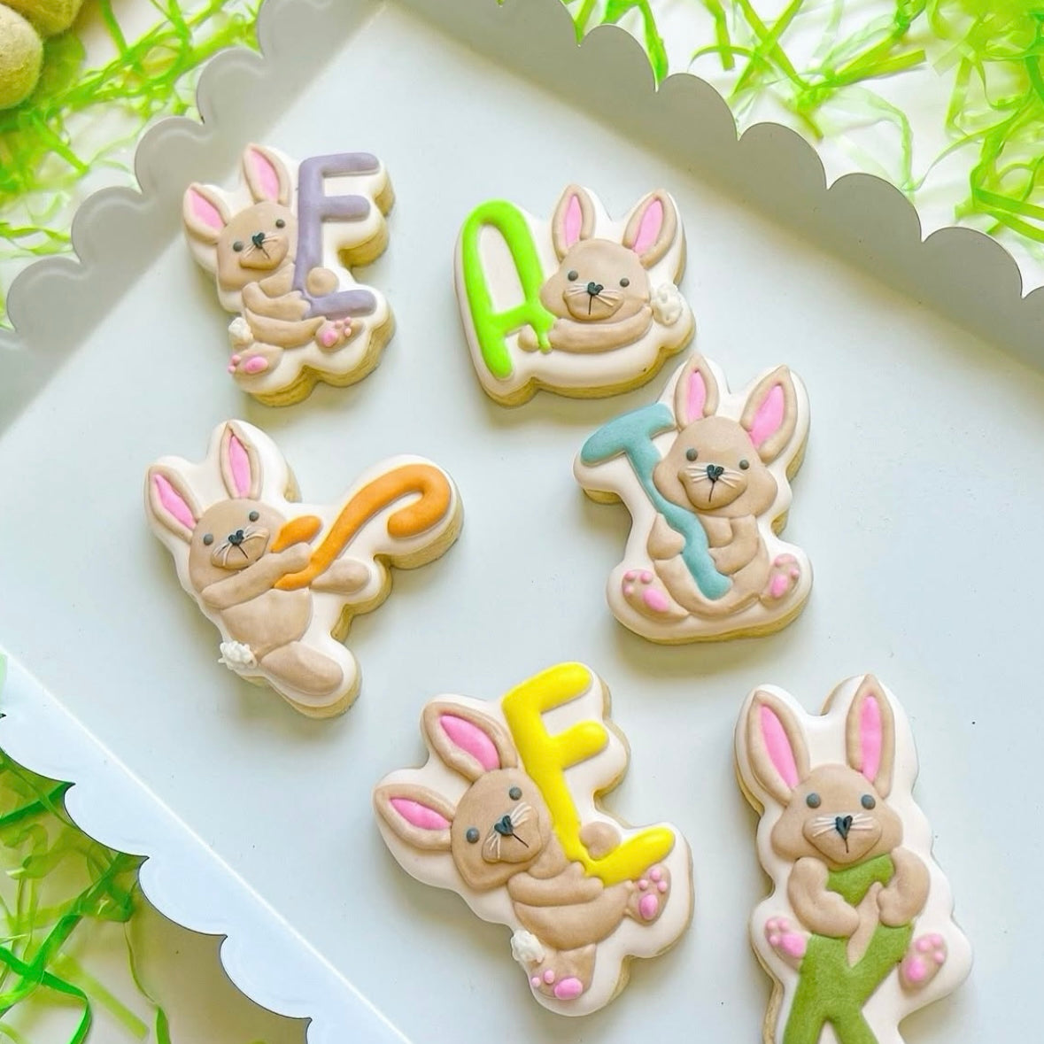 Playful bunnies holding E A S T E R letters stamp and cutter