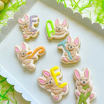 Playful bunnies holding E A S T E R letters stamp and cutter