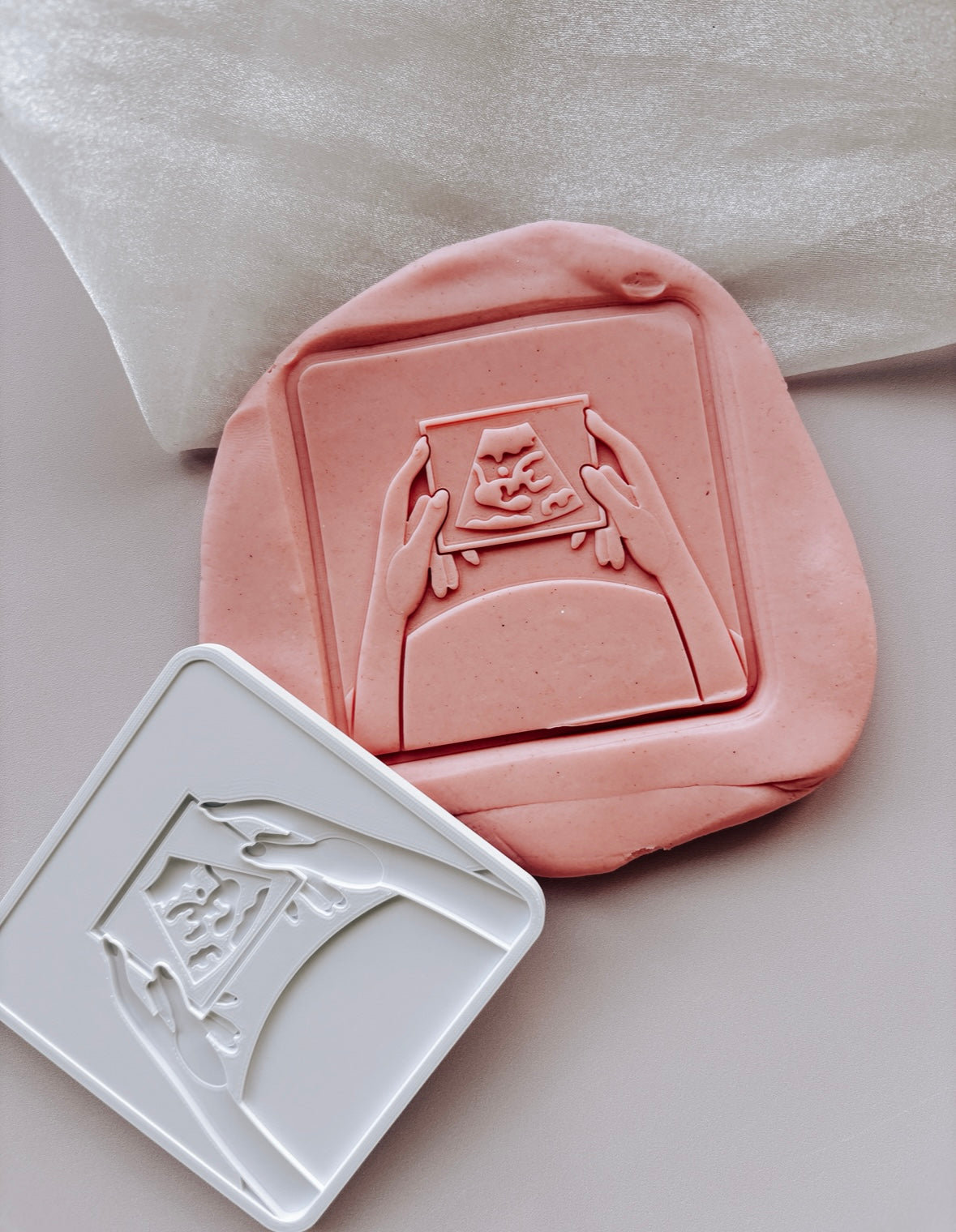 Hands holding baby scan photo stamp and cutter