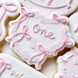 Bow covered cake with “one” stamp and cutter
