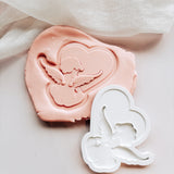 Cupid sitting near a heart shaped cloud stamp and cutter