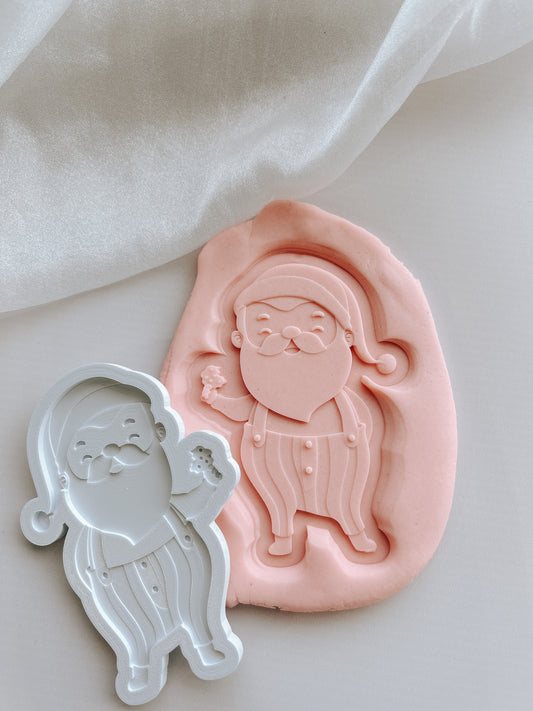 Santa Claus holding a cookie debosser and cutter