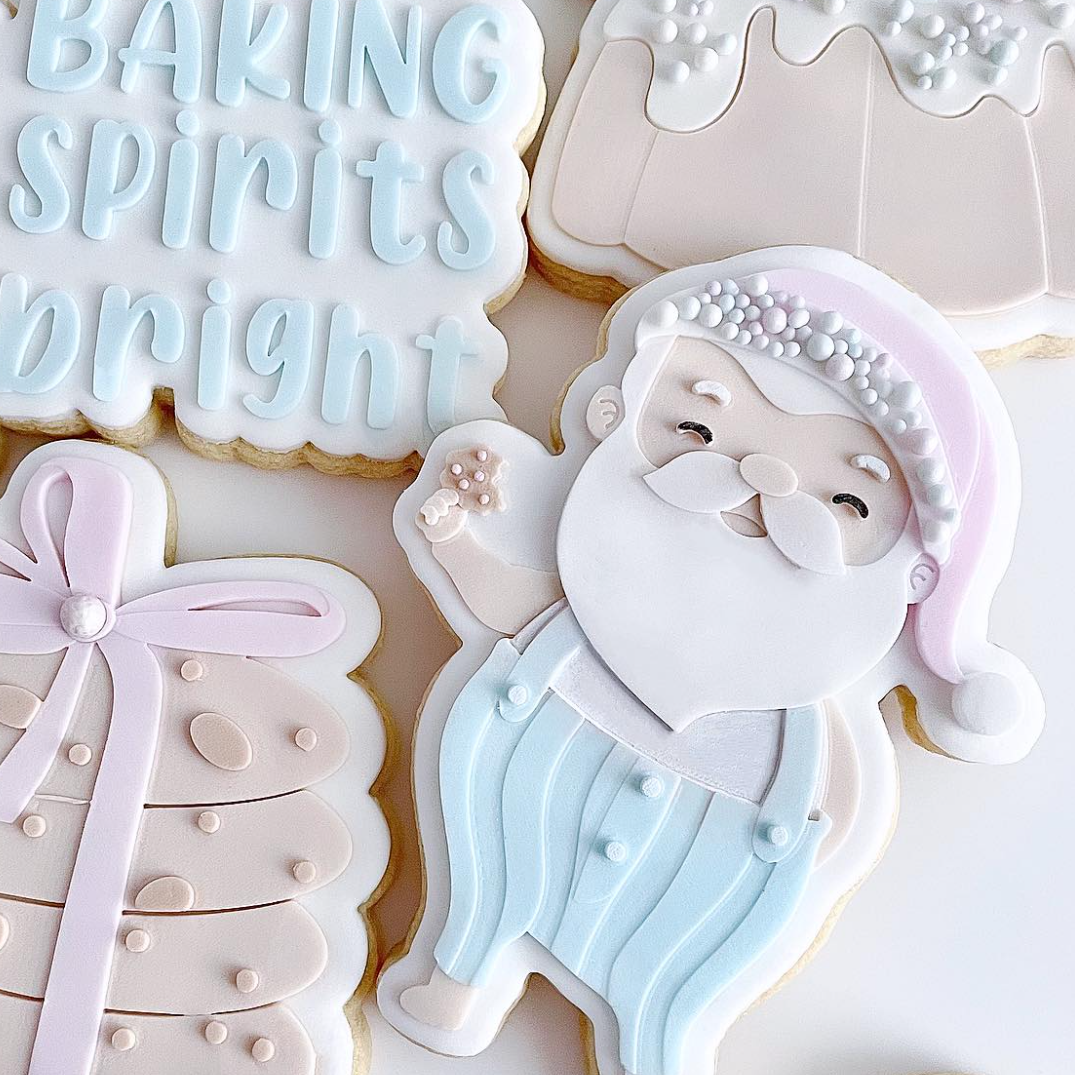 Santa Claus holding a cookie debosser and cutter